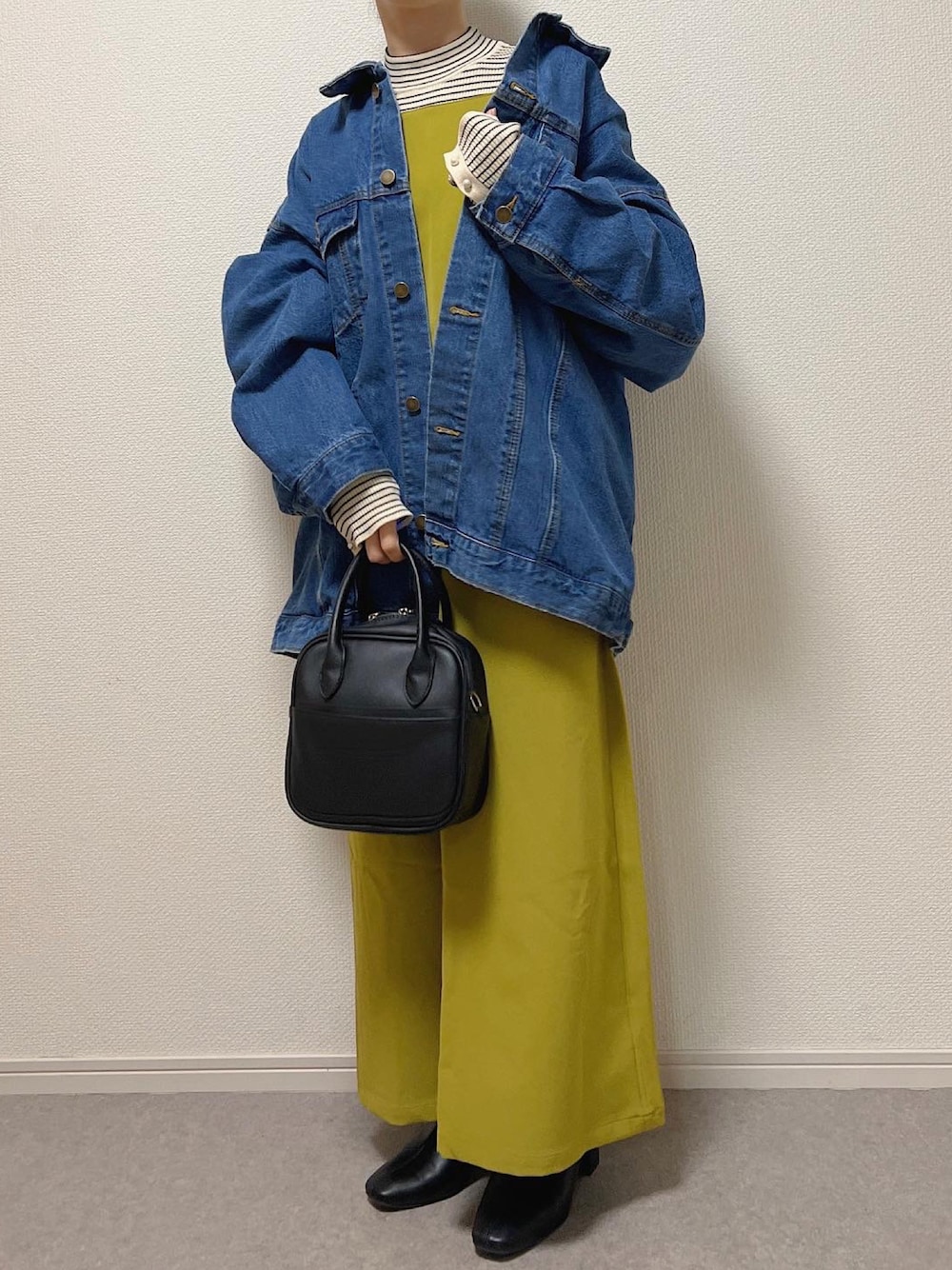 ブルー系のデニムジャケット、ブラック系のショルダーバッグ、ブラック系のブーツを着用したレディースの冬コーディネートの1枚目の写真