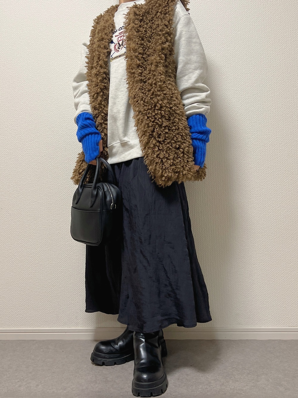 ブラック系のショルダーバッグ、ベージュ系のスウェット、ブラック系のスカートを着用したレディースの冬コーディネートの1枚目の写真