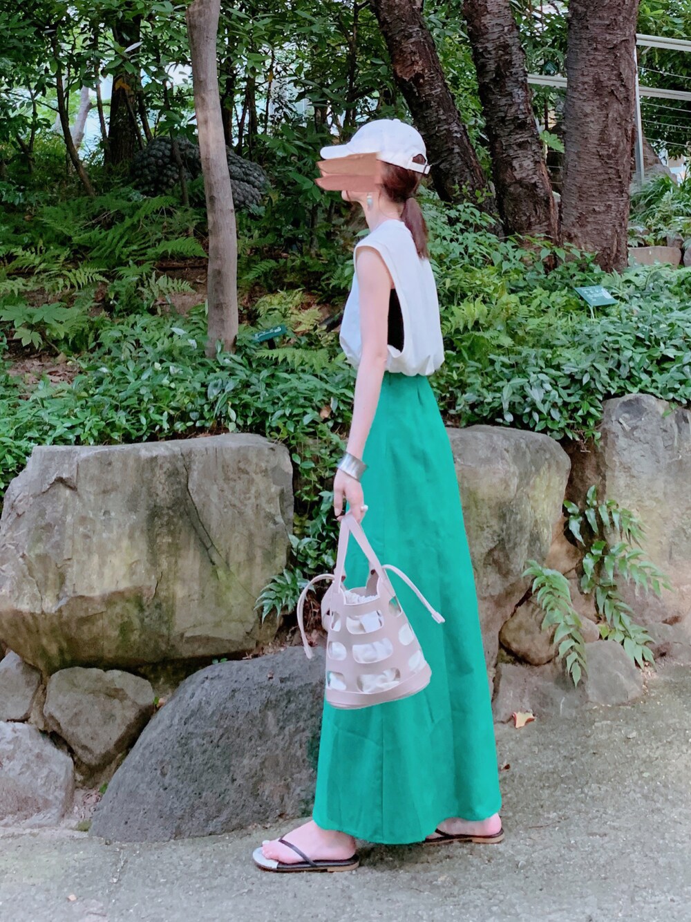 ホワイト系のタンクトップ、グリーン系のスカート、ベージュ系のトートバッグを着用したレディースの夏コーディネートの1枚目の写真