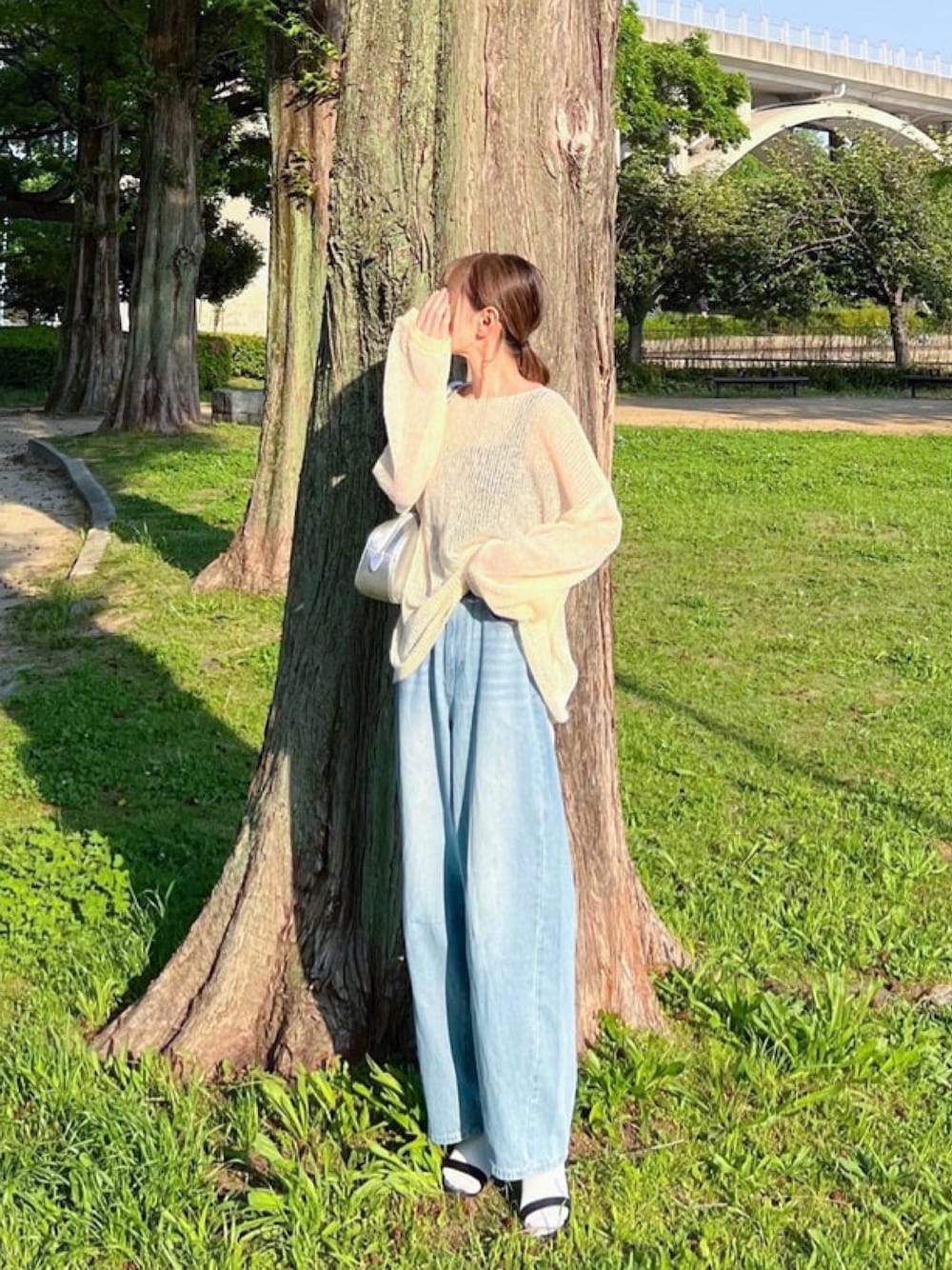 ホワイト系のニット/セーター、ブラック系のタンクトップ、ブルー系のデニムパンツを着用したレディースの冬コーディネートの1枚目の写真