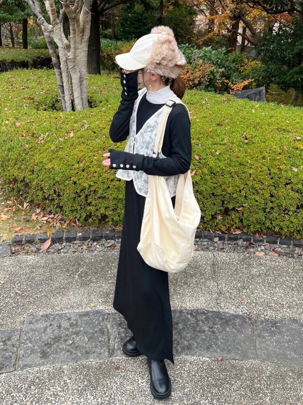 ブラック系のワンピース、ホワイト系のベスト、ホワイト系のショルダーバッグを着用したレディースの冬コーディネートの1枚目の写真