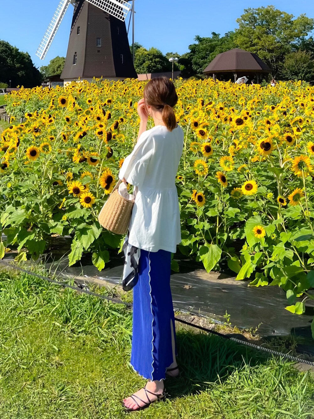 ホワイト系のTシャツ/カットソー、ブルー系のスカート、ベージュ系のかごバッグを着用したレディースの夏コーディネートの1枚目の写真