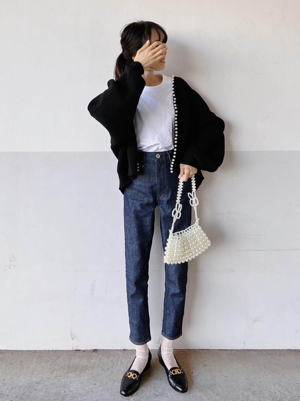 ホワイト系のTシャツ/カットソー、ブラック系のカーディガン/ボレロ、ブルー系のデニムパンツを着用したレディースの秋コーディネートの1枚目の写真