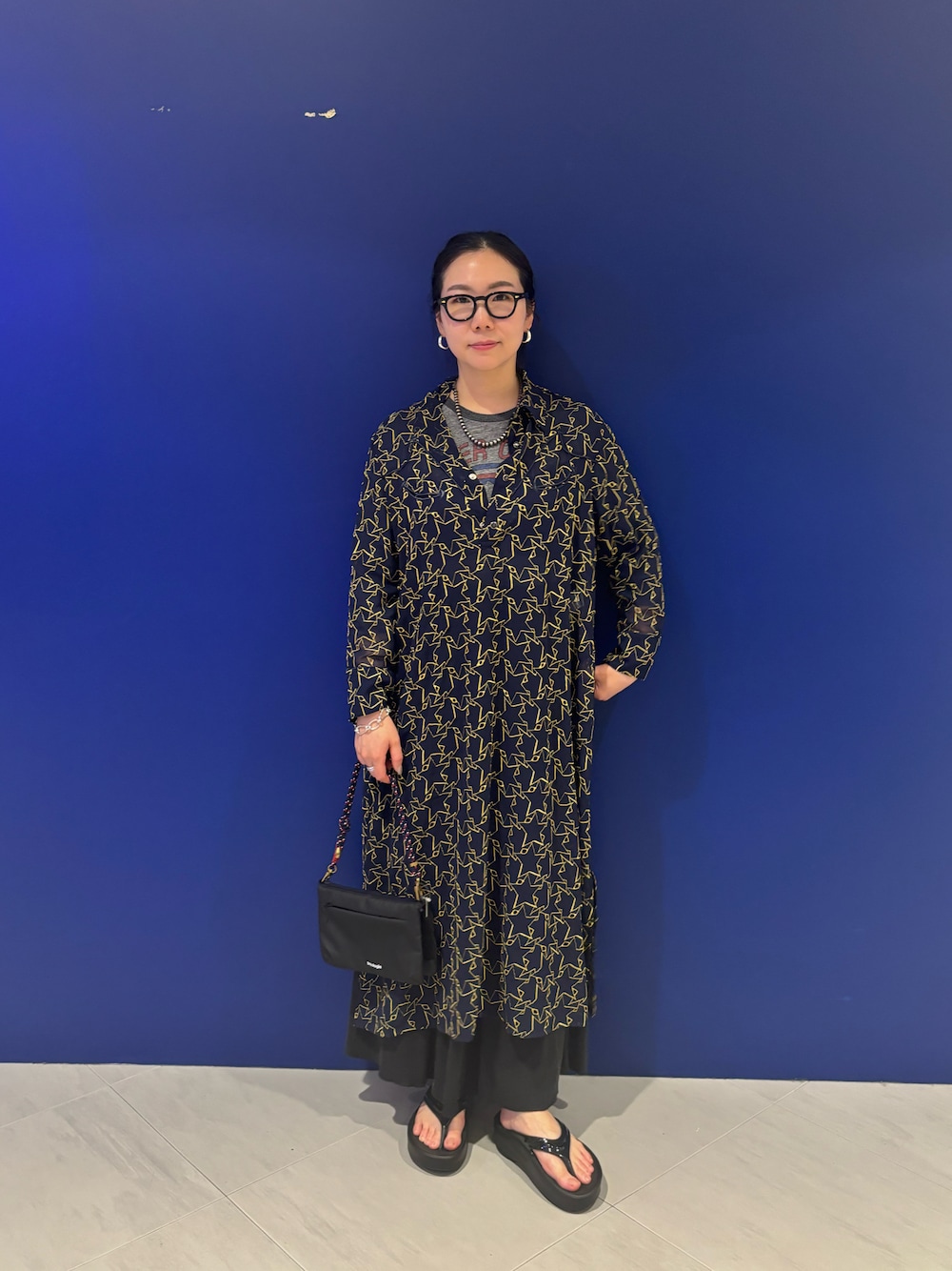 ブラック系のサンダル、ブラック系のショルダーバッグ、ブルー系のスマホグッズを着用したレディースの春コーディネートの1枚目の写真