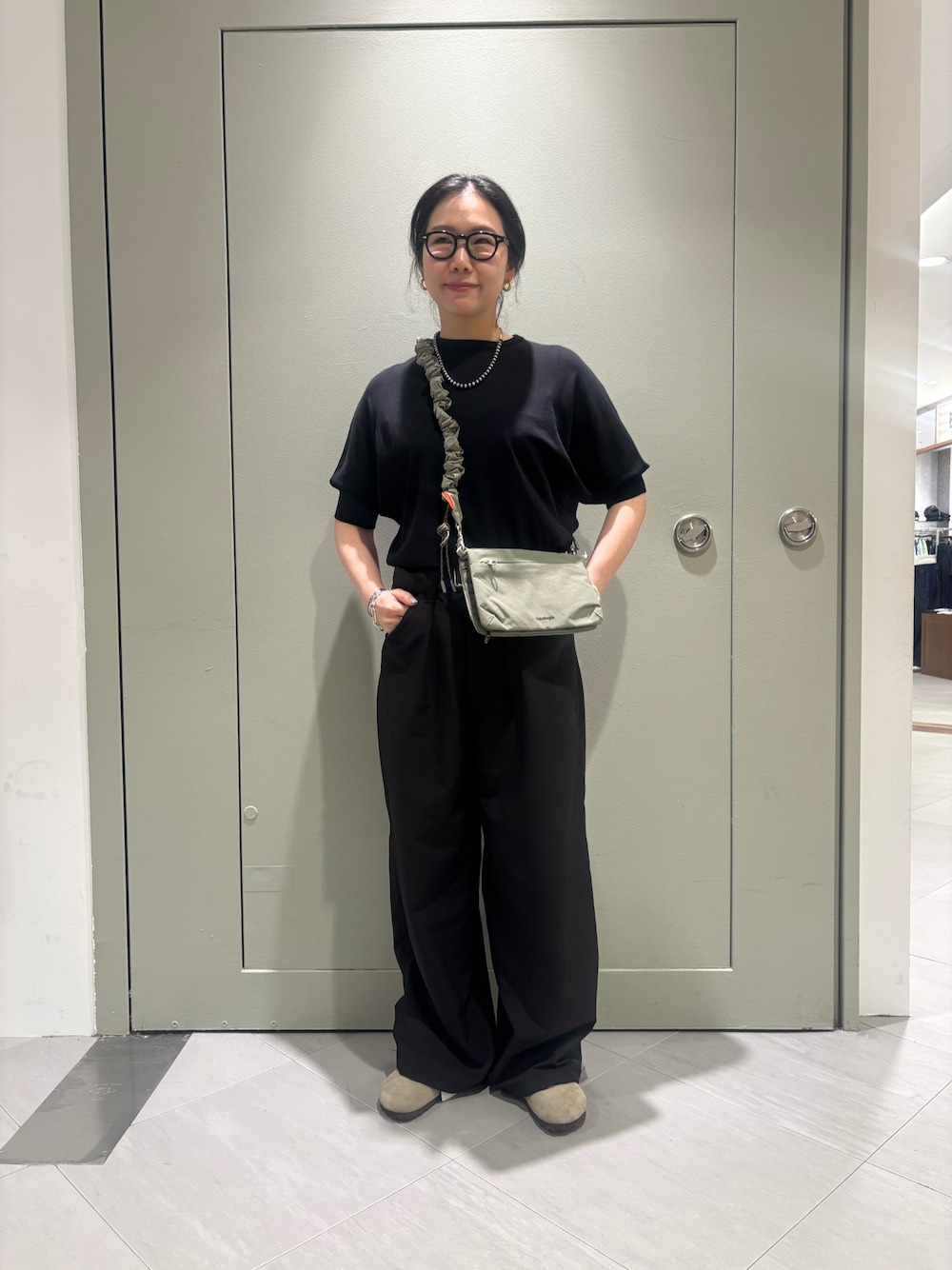 「夏、ショルダーバッグ、ブラックコーデ、BEAVER、ワイドパンツ、ビルケンシュトック、ボストン、黒ニット、黒Tシャツ、BEAVER名古屋」｜「TopologieのTopologie/トポロジー Bungee Strap バンジーストラップ【ストラップ単体】（スマホグッズ、ベージュ系）」を使った、小林さん（レディース・155cm）の春コーディネートの1枚目の写真