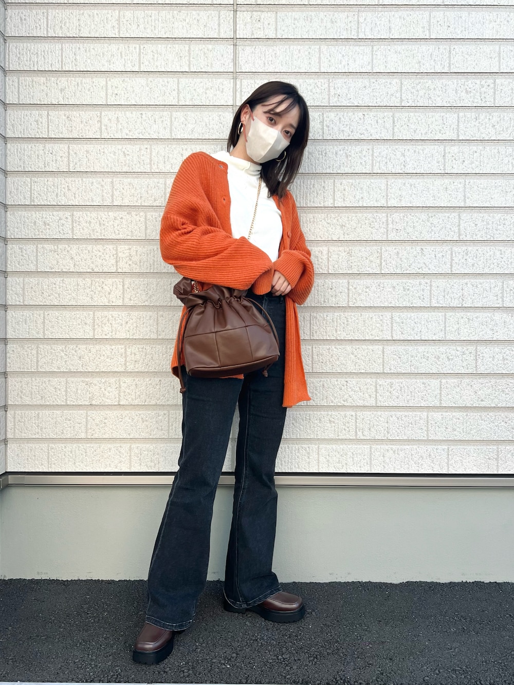 オレンジ系のカーディガン/ボレロ、ホワイト系のTシャツ/カットソー、ブラウン系のバッグを着用したレディースの秋コーディネートの1枚目の写真