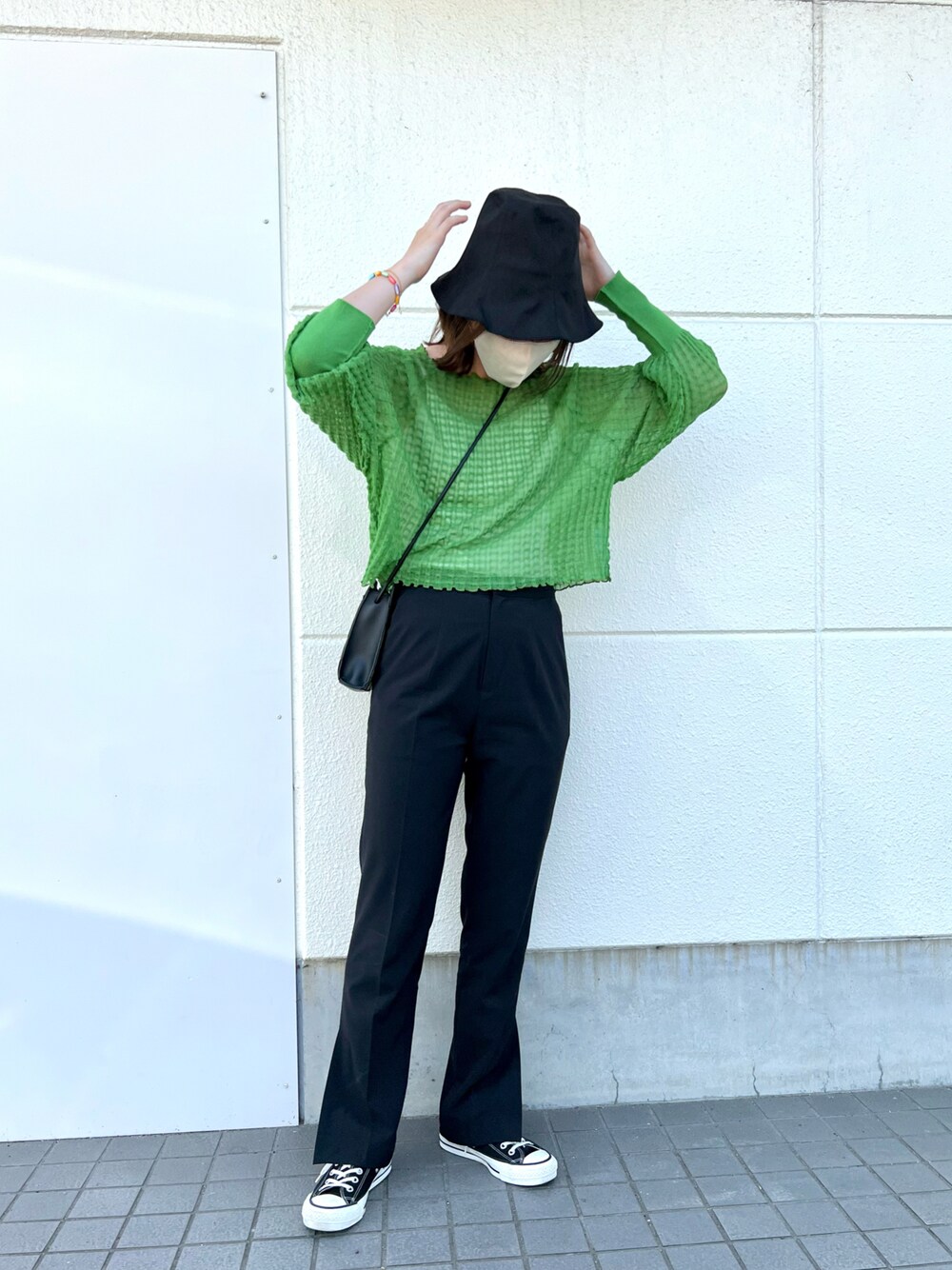 グリーン系のニット/セーター、ホワイト系のキャミソール、ブラック系のスラックスを着用したレディースの春コーディネートの1枚目の写真