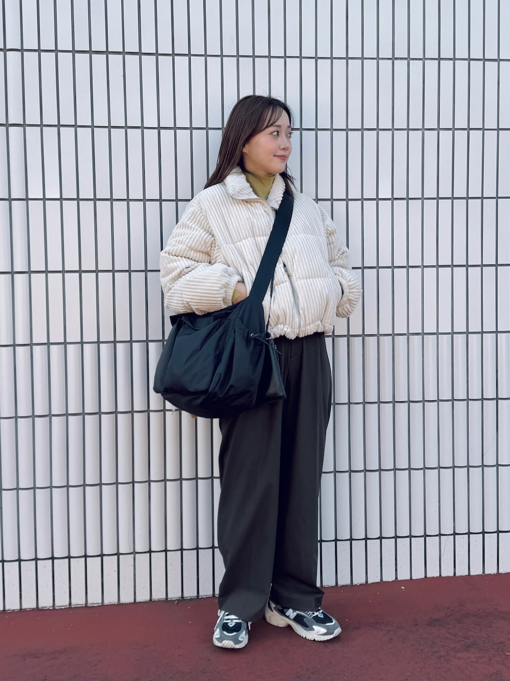 ブラック系のショルダーバッグ、ブラウン系のスラックス、ブラック系のスニーカーを着用したレディースの冬コーディネートの1枚目の写真