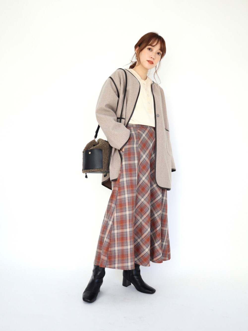 ブラウン系のノーカラーコート、ホワイト系のトップス、ブラウン系のスカートを着用したレディースの秋コーディネートの1枚目の写真