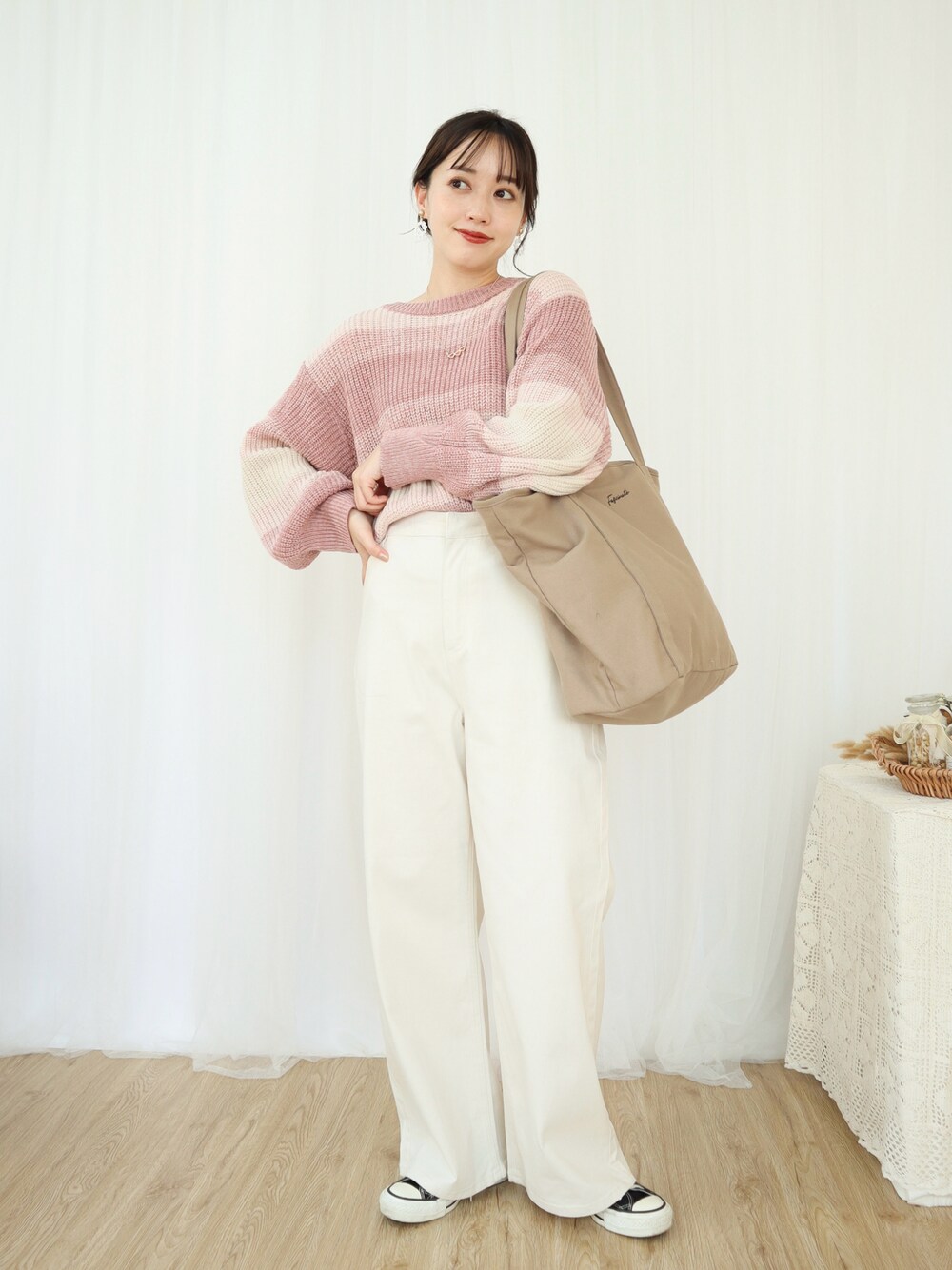 ピンク系のニット/セーター、ホワイト系のパンツ、ベージュ系のバッグを着用したレディースの冬コーディネートの1枚目の写真