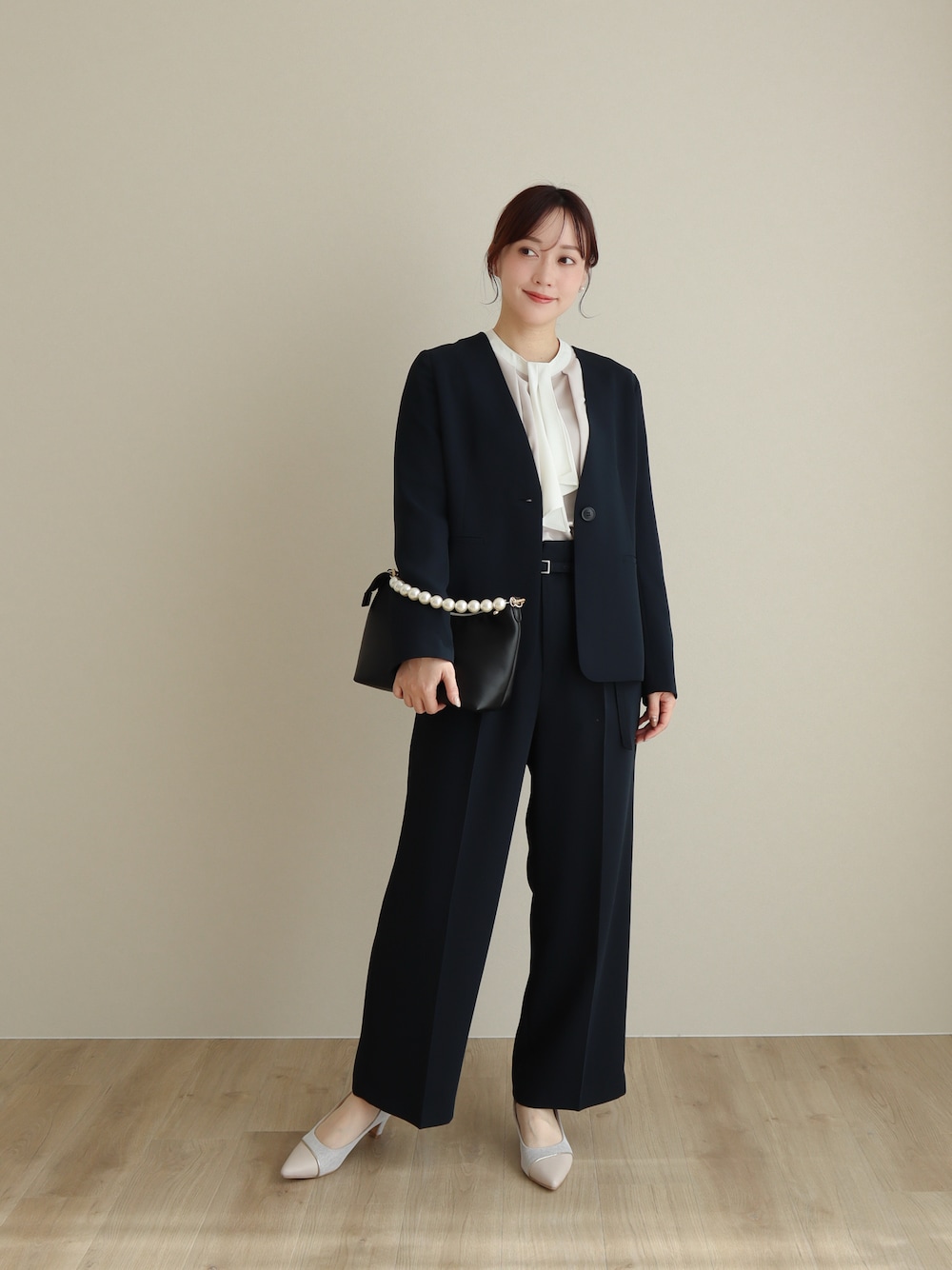 ブルー系のスーツセット、ピンク系のパンプス、ブラック系のバッグを着用したレディースの冬コーディネートの1枚目の写真