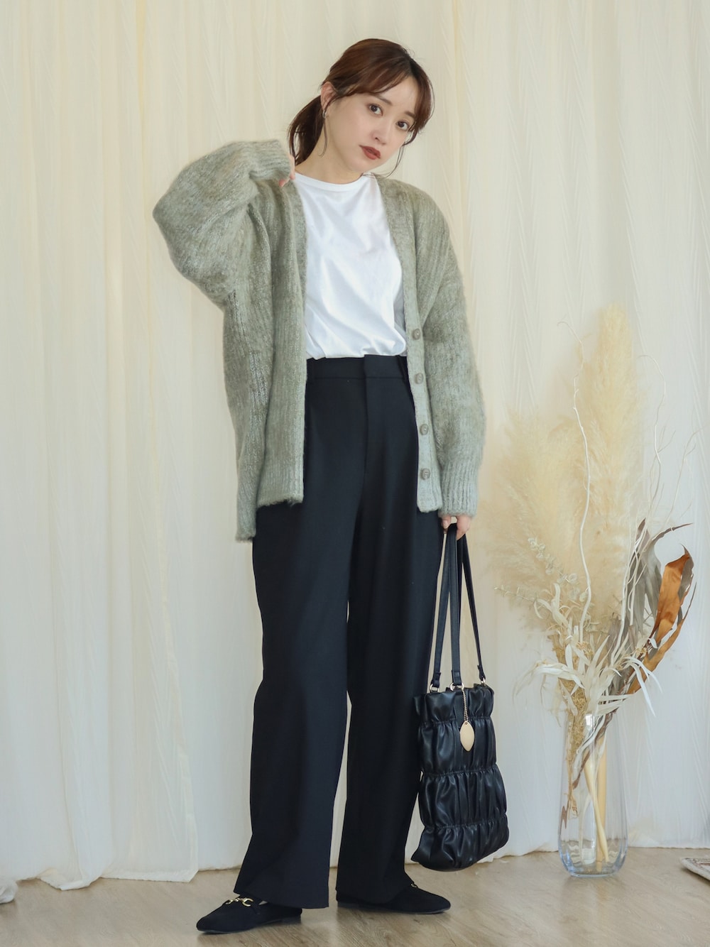 グリーン系のカーディガン/ボレロ、ブラック系のパンツ、ブラック系のバッグを着用したレディースの秋コーディネートの1枚目の写真