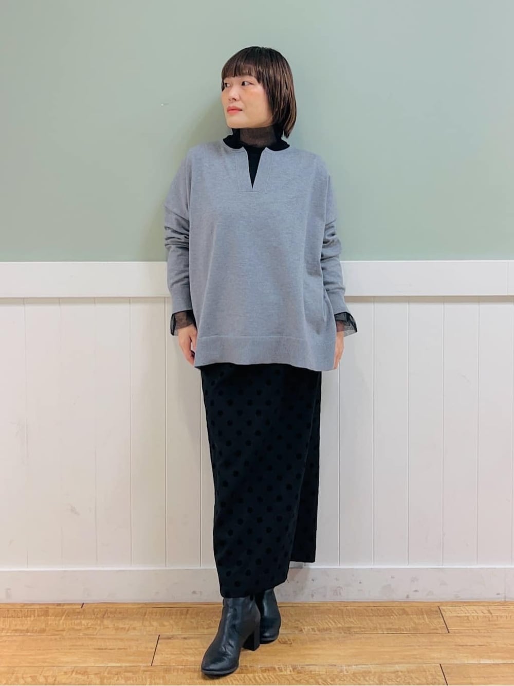 グレー系のニット/セーター、ブラック系のTシャツ/カットソー、グレー系のスカートを着用したレディースの冬コーディネートの1枚目の写真
