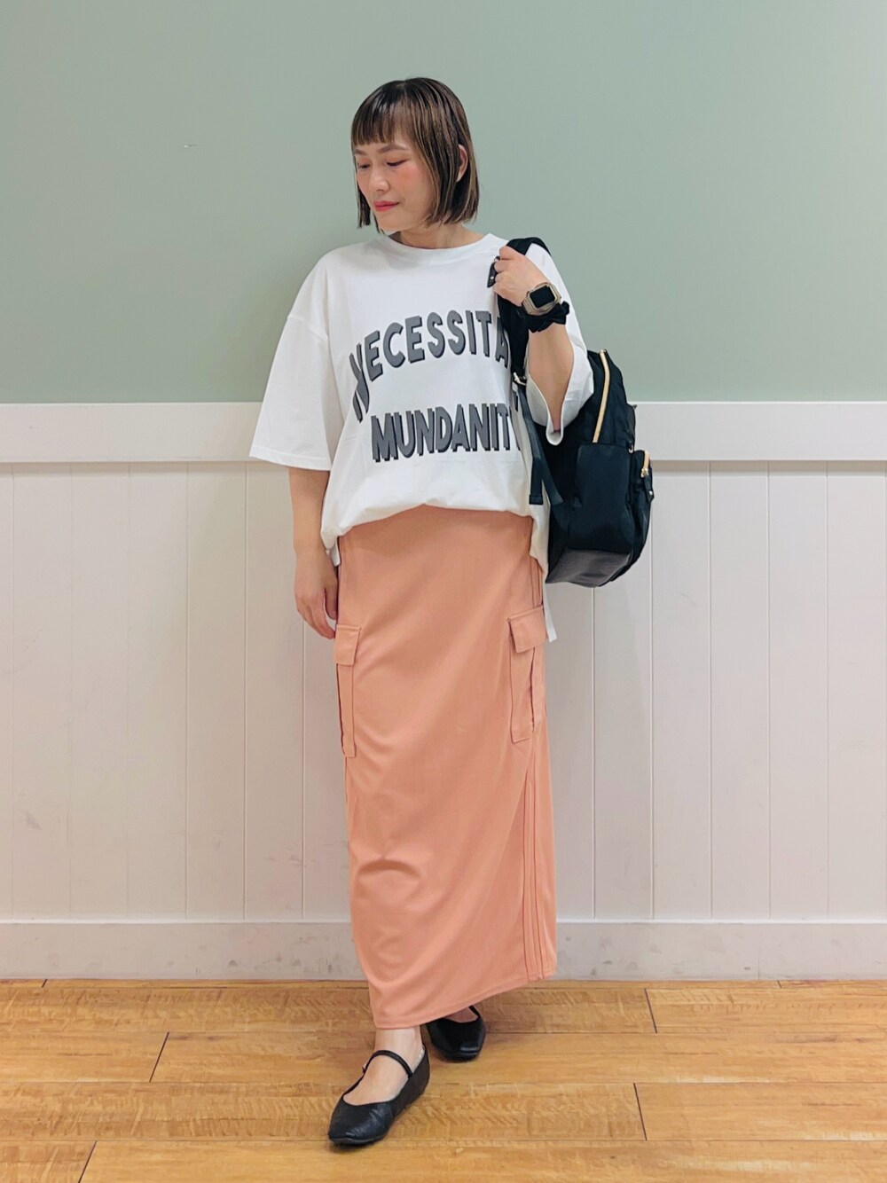 ブラック系のバックパック/リュック、ホワイト系のTシャツ/カットソー、オレンジ系のスカートを着用したレディースの夏コーディネートの1枚目の写真