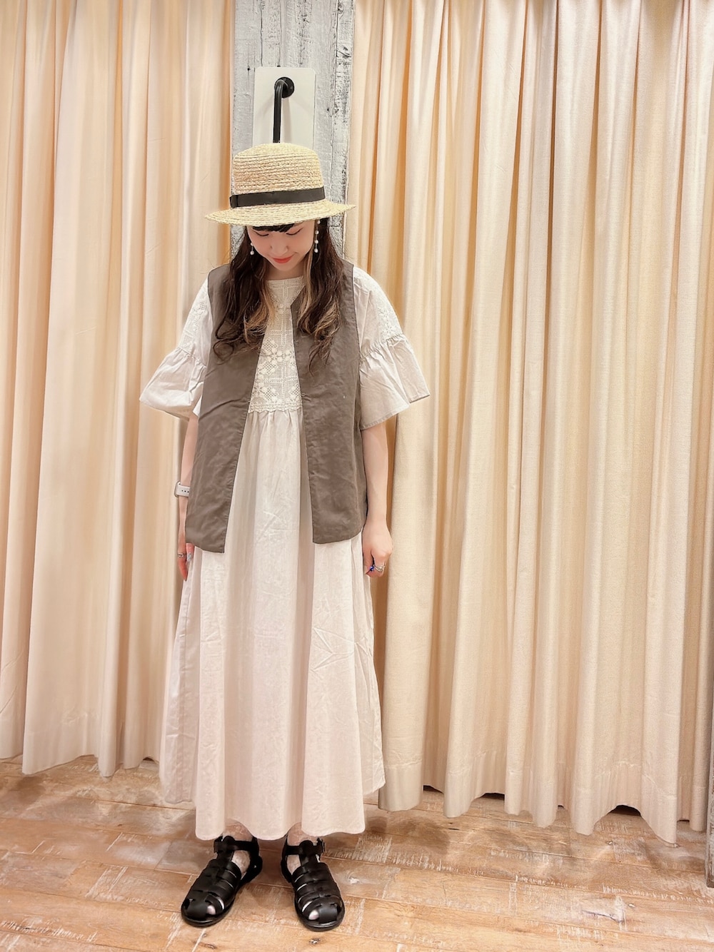 ホワイト系のワンピース、ブラック系のサンダル、ホワイト系のベストを着用したレディースの春コーディネートの1枚目の写真