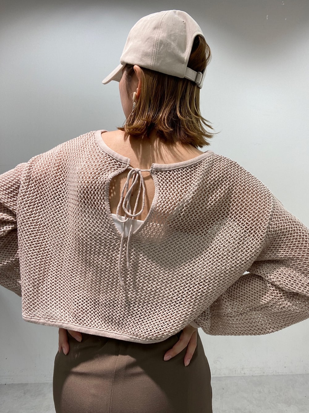 ブラウン系のスカート、ベージュ系のニット/セーター、ホワイト系のスニーカーを着用したレディースの春コーディネートの4枚目の写真