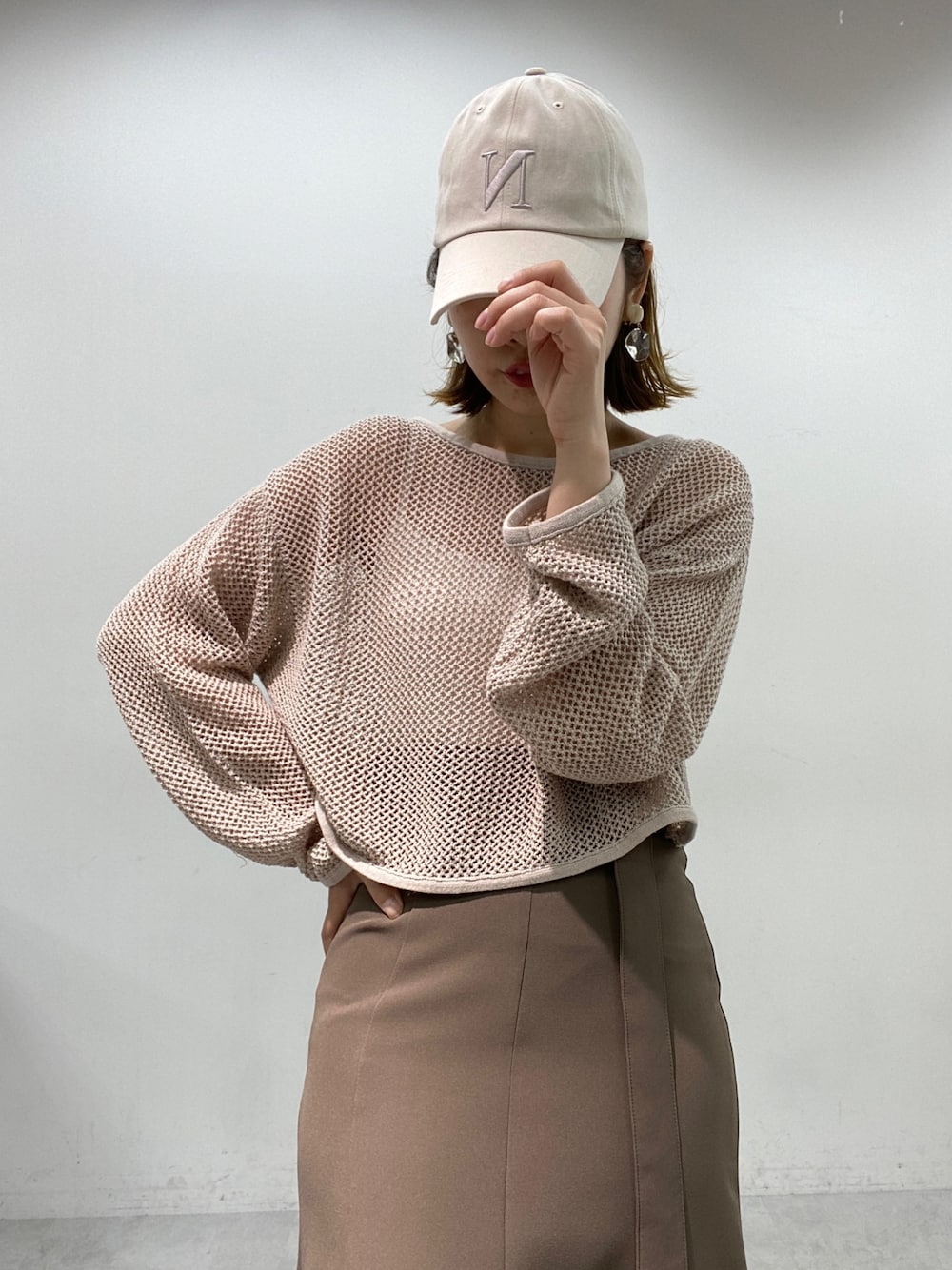 ブラウン系のスカート、ベージュ系のニット/セーター、ホワイト系のスニーカーを着用したレディースの春コーディネートの3枚目の写真