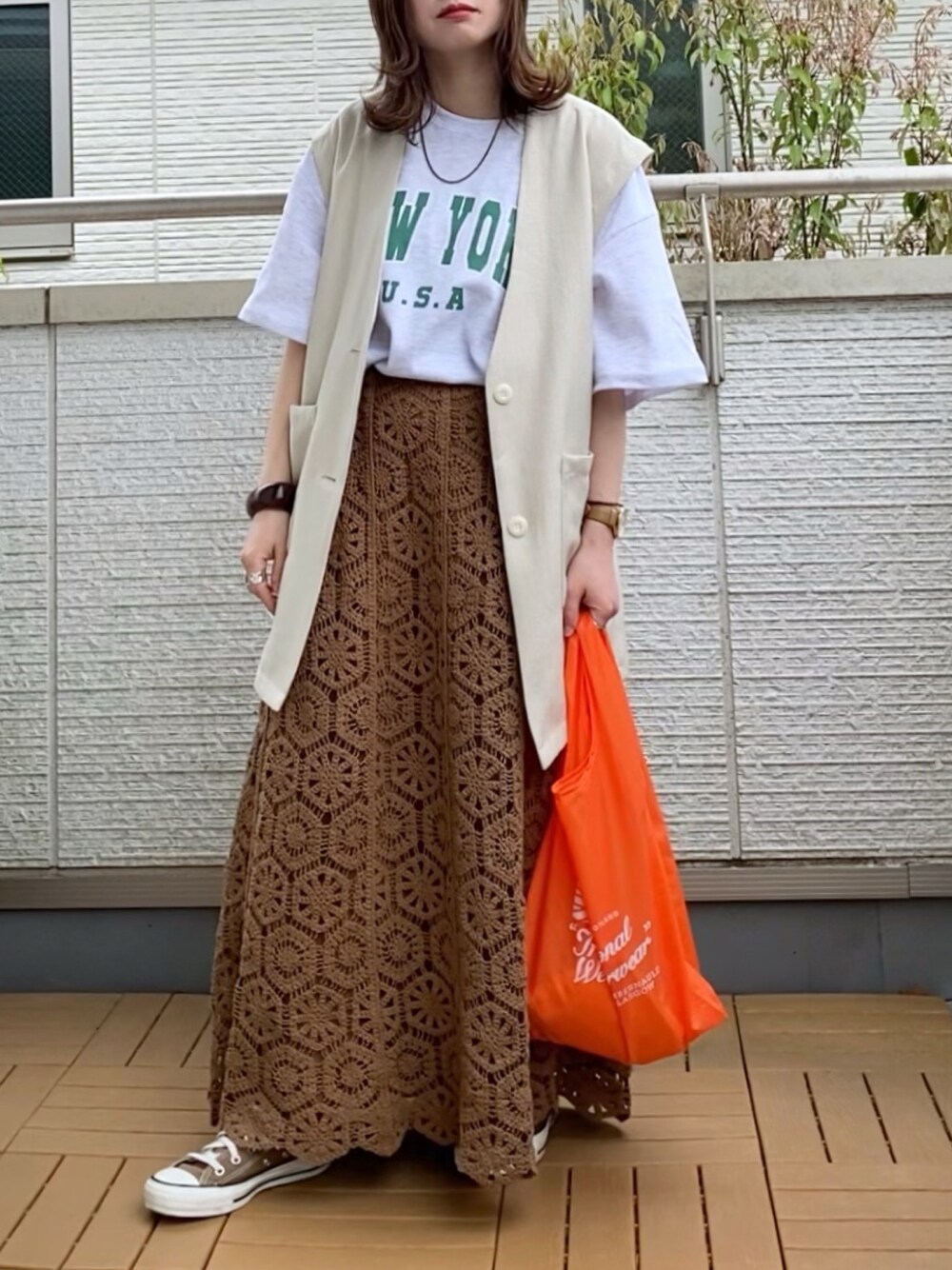 ホワイト系のTシャツ/カットソー、ベージュ系のベスト、ブラウン系のスカートを着用したレディースの春コーディネートの1枚目の写真