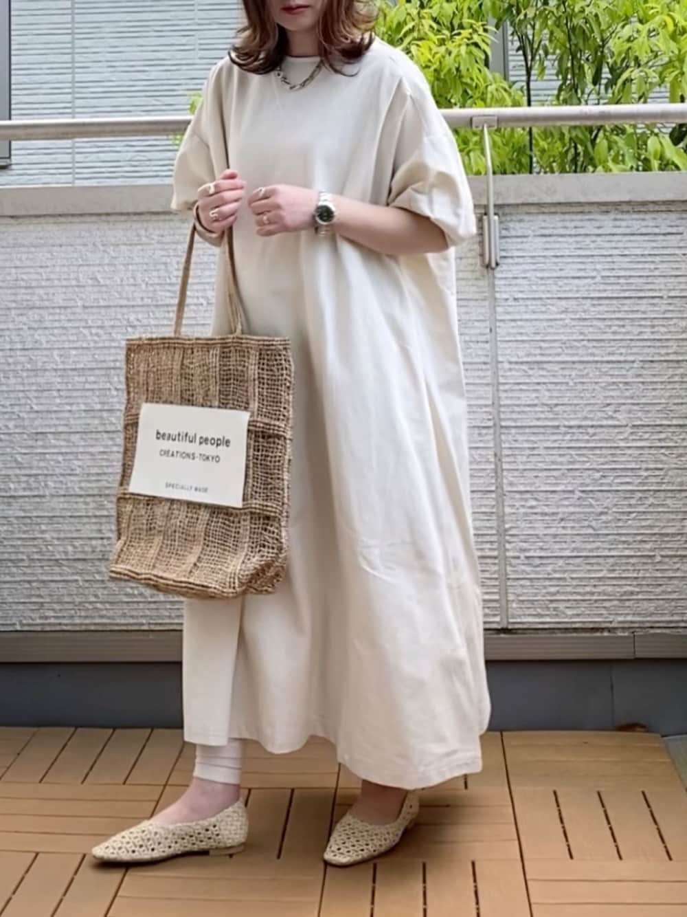 ホワイト系のワンピース、ベージュ系のバッグ、ホワイト系のパンプスを着用したレディースの春コーディネートの1枚目の写真