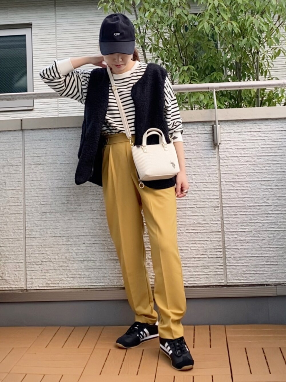ホワイト系のショルダーバッグ、ブラック系のベスト、ブラック系のTシャツ/カットソーを着用したレディースの秋コーディネートの1枚目の写真