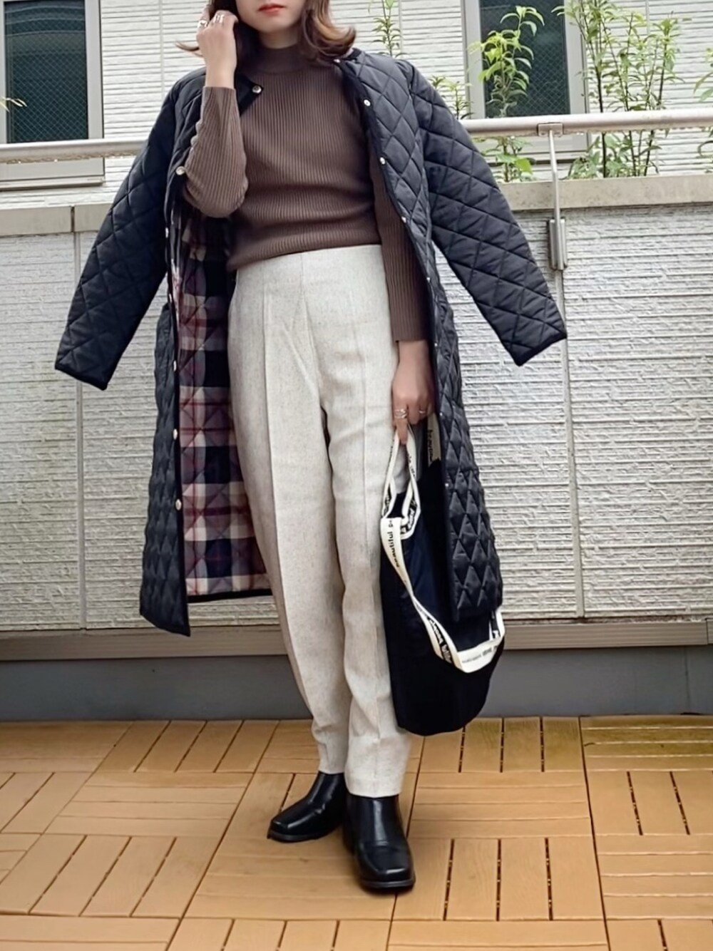 ブラック系のノーカラーコート、ブラウン系のニット/セーター、ホワイト系のその他パンツを着用したレディースの秋コーディネートの1枚目の写真