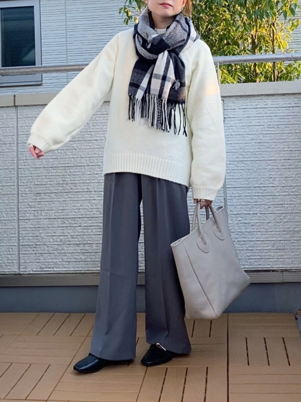 ホワイト系のニット/セーター、グレー系のスラックス、ベージュ系のトートバッグを着用したレディースの秋コーディネートの1枚目の写真