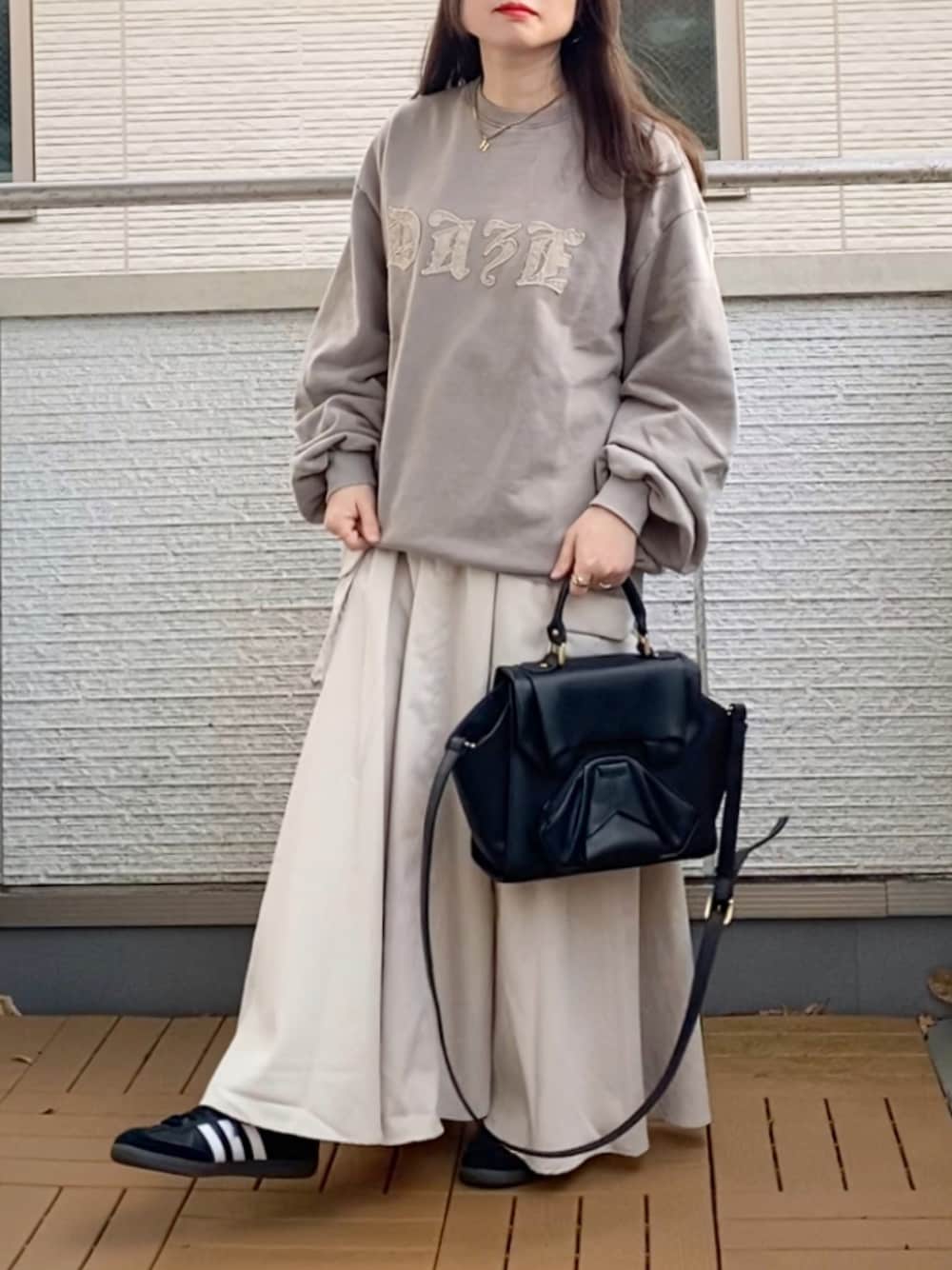 ベージュ系のトップス、ホワイト系のスカート、ブラック系のハンドバッグを着用したレディースの冬コーディネートの1枚目の写真