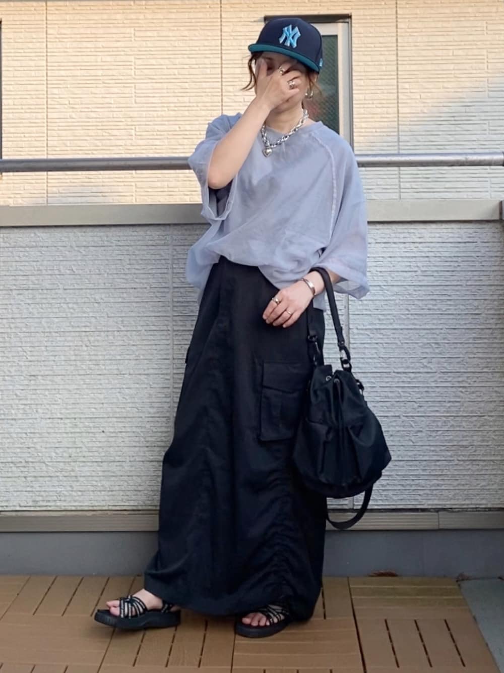 グレー系のその他トップス、ブラック系のスカート、ブラック系のショルダーバッグを着用したレディースの夏コーディネートの1枚目の写真