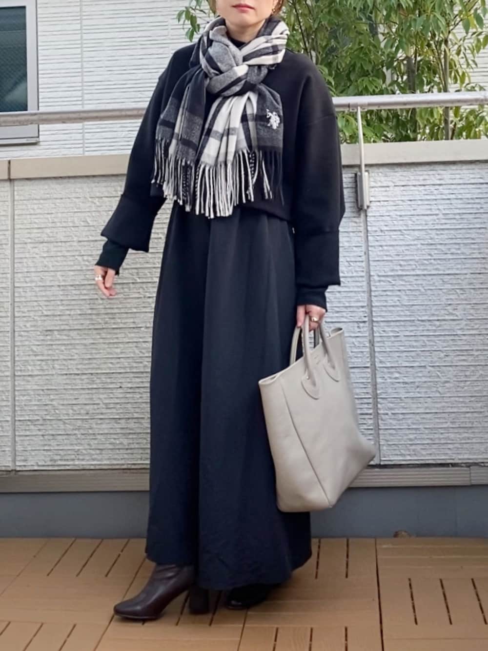 ブラック系のワンピース、ベージュ系のトートバッグ、ブラウン系のブーツを着用したレディースの秋コーディネートの1枚目の写真