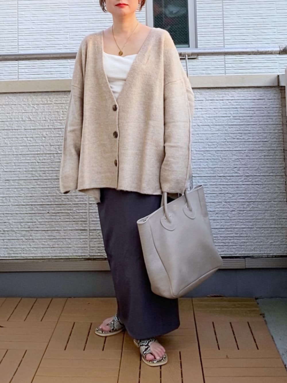 ベージュ系のカーディガン/ボレロ、グレー系のスカート、ベージュ系のトートバッグを着用したレディースの秋コーディネートの1枚目の写真