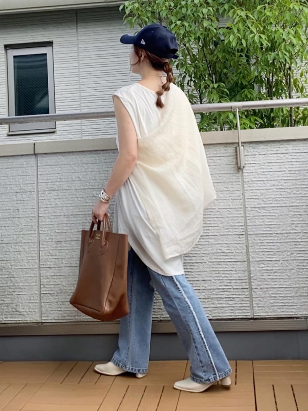 ホワイト系のタンクトップ、ブルー系のデニムパンツ、ブラウン系のトートバッグを着用したレディースの夏コーディネートの1枚目の写真