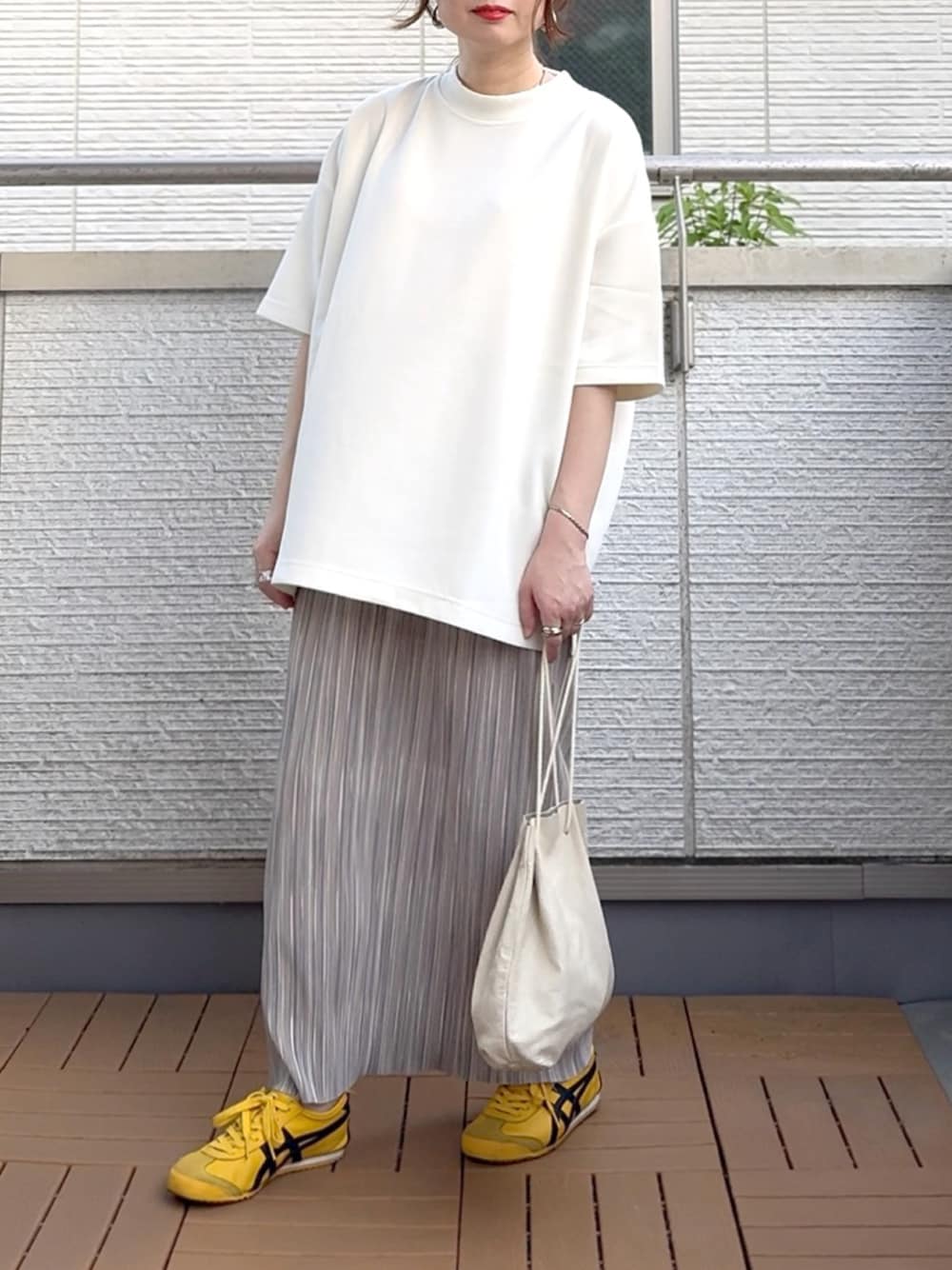 グレー系のスカート、ホワイト系のTシャツ/カットソー、イエロー系のスニーカーを着用したレディースの夏コーディネートの1枚目の写真
