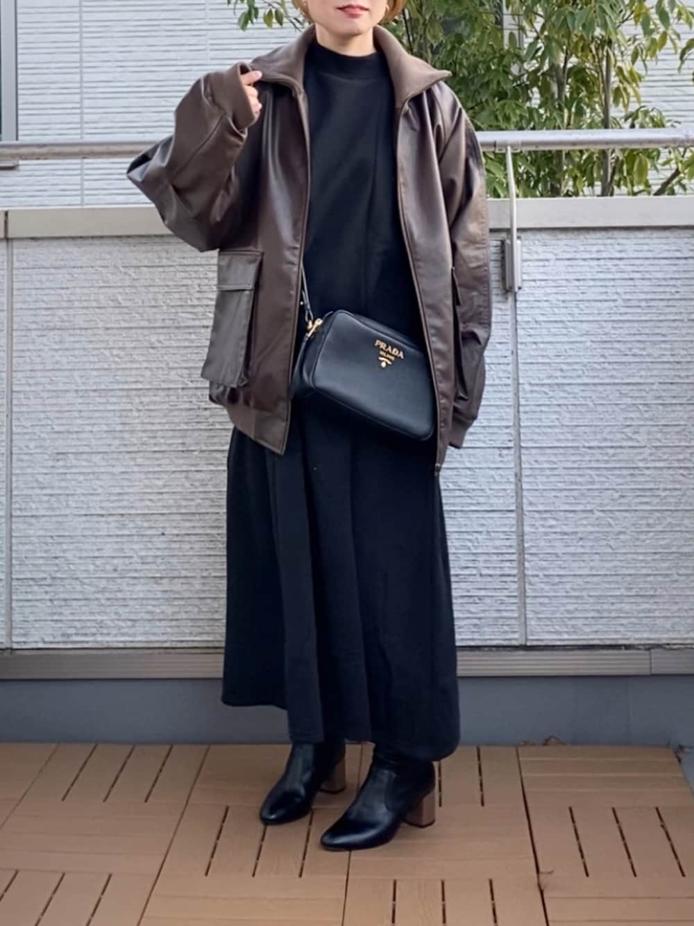 ブラック系のワンピース、ブラウン系のライダースジャケット、ブラック系のブーツを着用したレディースの冬コーディネートの1枚目の写真