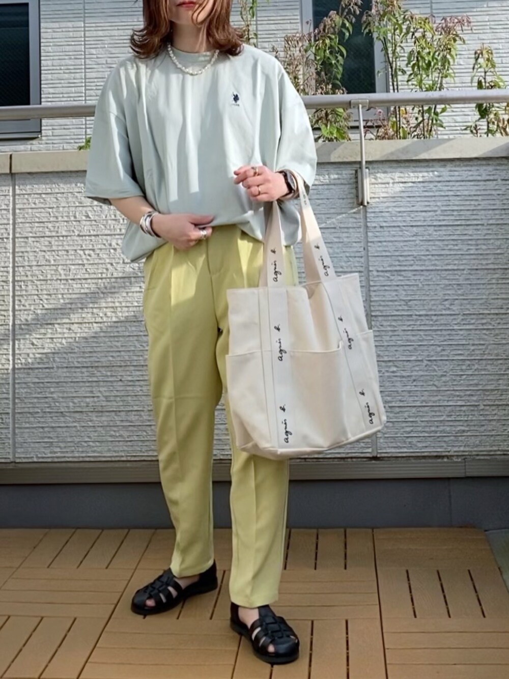 グリーン系のTシャツ/カットソー、ベージュ系のトートバッグ、ブラック系のサンダルを着用したレディースの春コーディネートの1枚目の写真