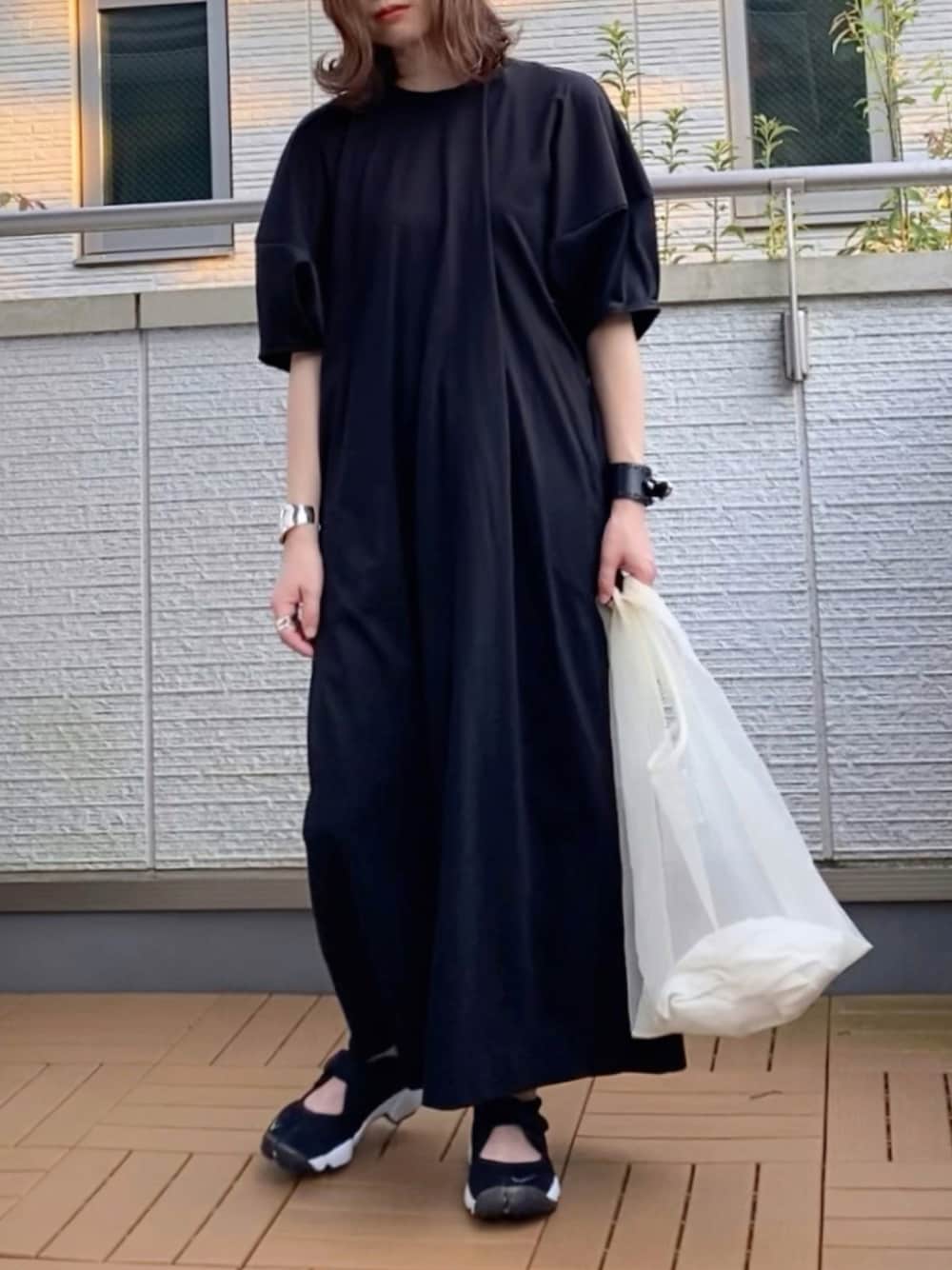 ブラック系のワンピース、ホワイト系のハンドバッグ、ブラック系のスニーカーを着用したレディースの夏コーディネートの1枚目の写真