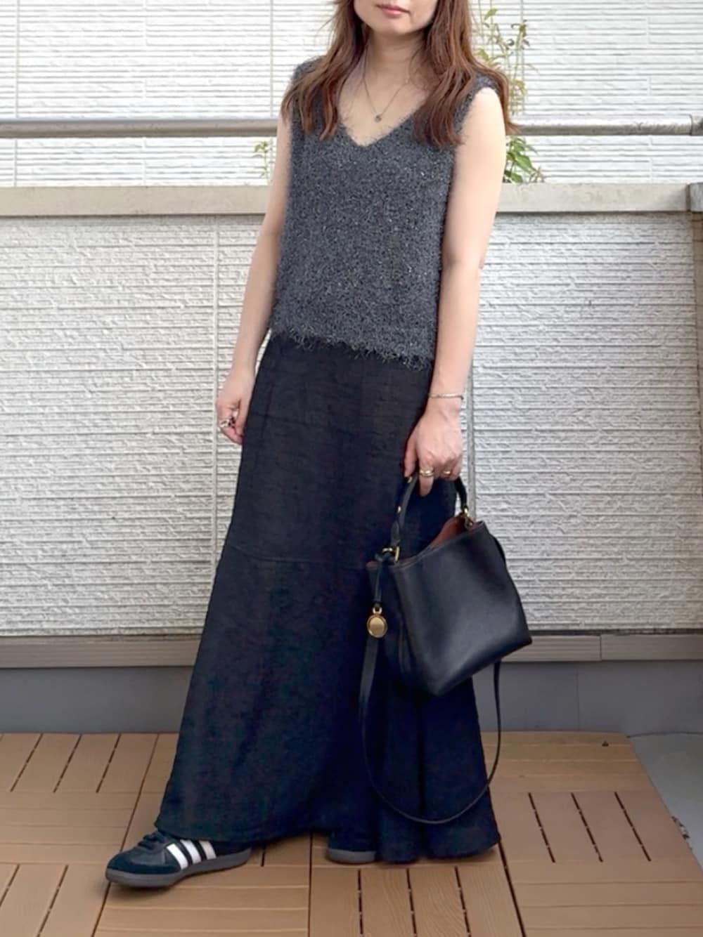 グレー系のベスト、ブラック系のワンピース、ブラック系のショルダーバッグを着用したレディースの夏コーディネートの1枚目の写真