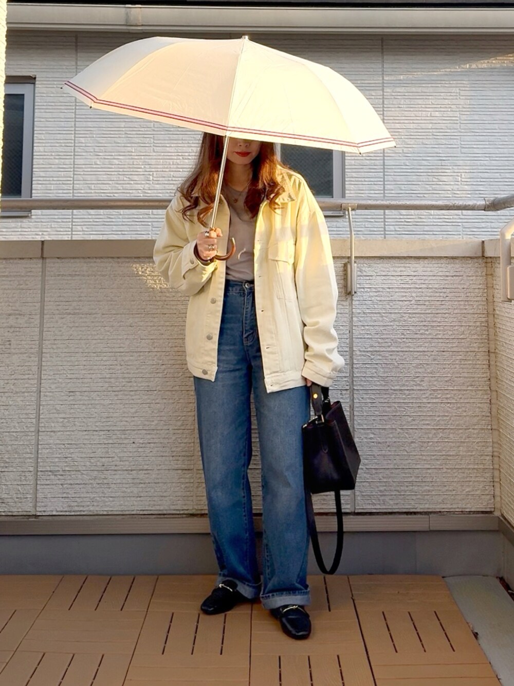 ホワイト系のデニムジャケット、ブルー系のデニムパンツ、ブラック系のショルダーバッグを着用したレディースの春コーディネートの1枚目の写真