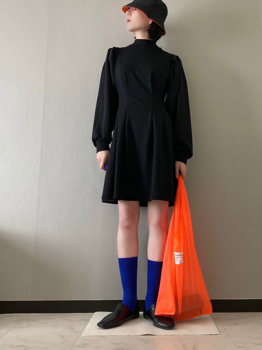 ブラック系のワンピース、オレンジ系のエコバッグ/サブバッグ、ブルー系のソックス/靴下を着用したレディースの冬コーディネートの1枚目の写真
