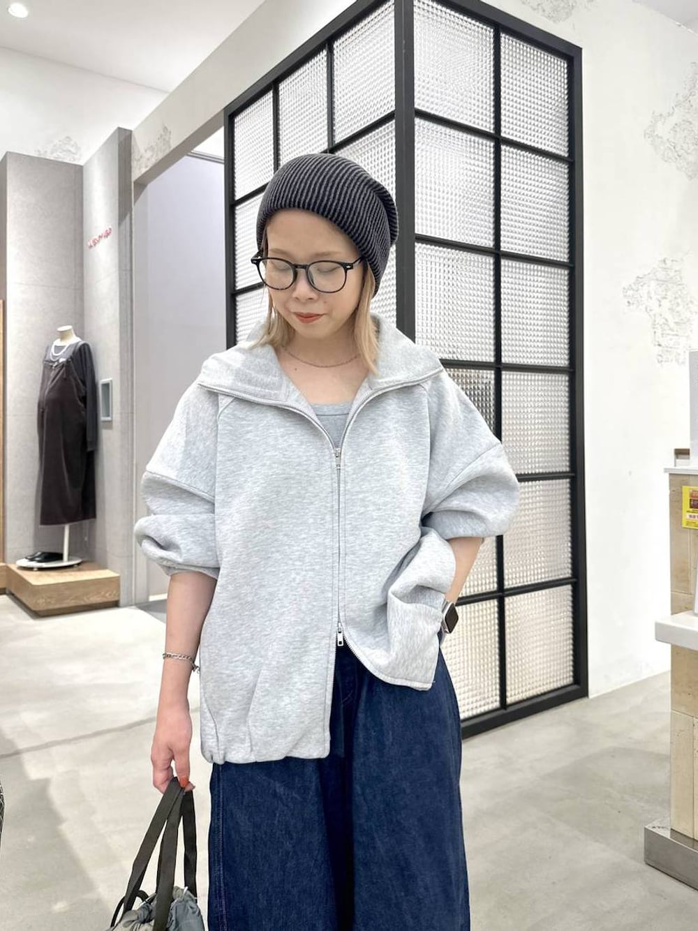 グリーン系のショルダーバッグ、ブルー系のデニムパンツ、ブラック系のニットキャップ/ビーニーを着用したレディースの秋コーディネートの1枚目の写真