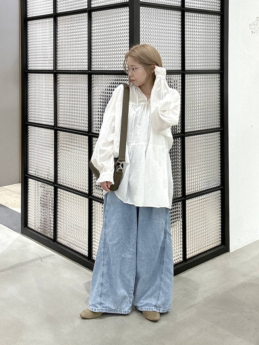 ブラウン系のショルダーバッグ、ブルー系のデニムパンツ、ベージュ系のパンプスを着用したレディースの春コーディネートの1枚目の写真