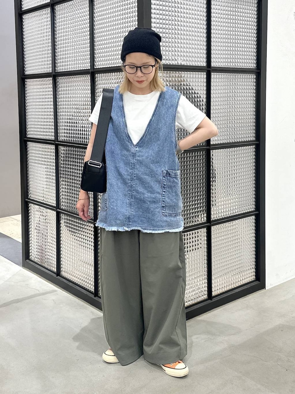 ブラック系のショルダーバッグ、ブルー系のベスト、グリーン系のその他パンツを着用したレディースの夏コーディネートの1枚目の写真