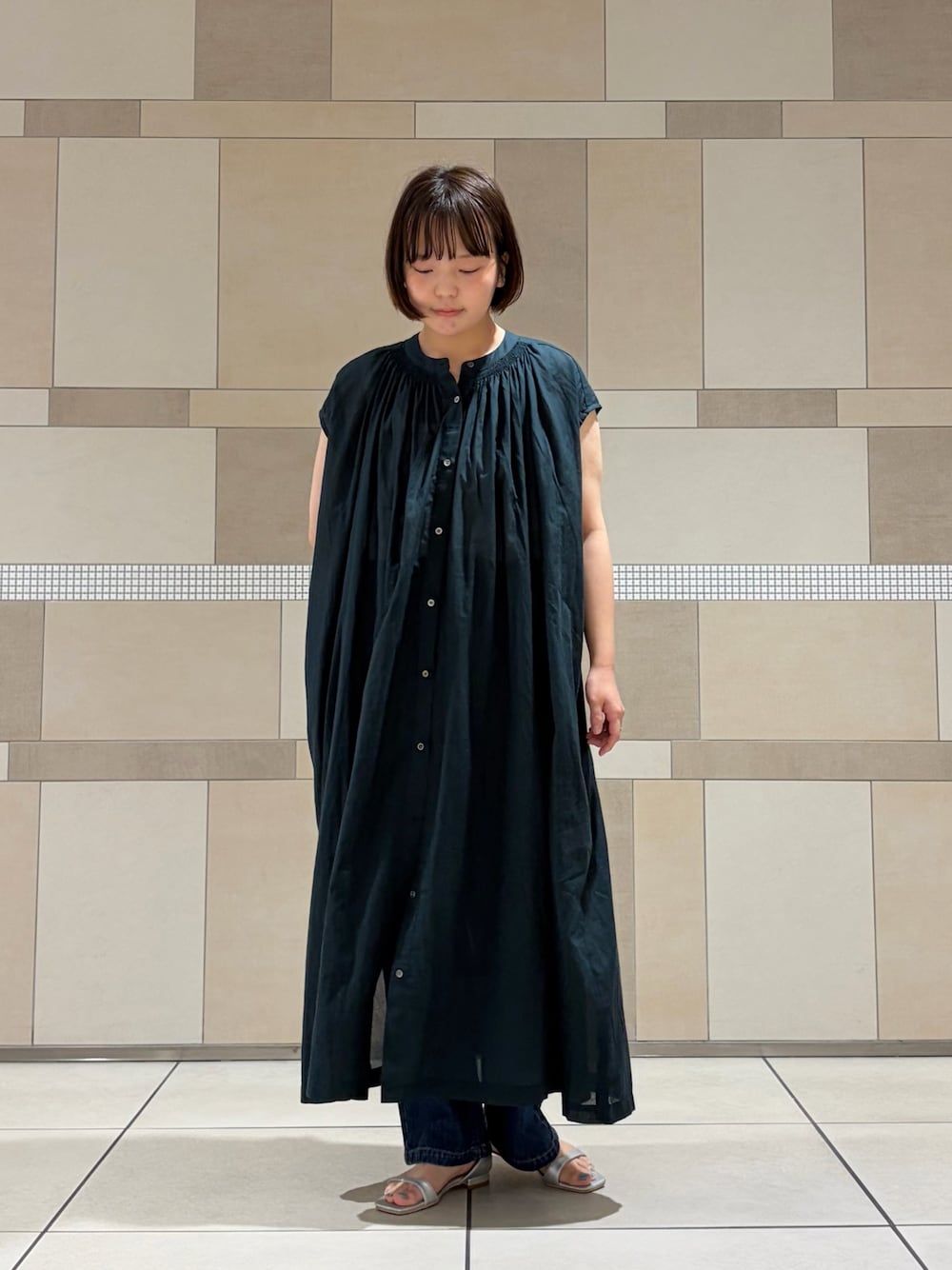 グリーン系のワンピース、ブルー系のデニムパンツ、シルバー系のサンダルを着用したレディースの夏コーディネートの1枚目の写真