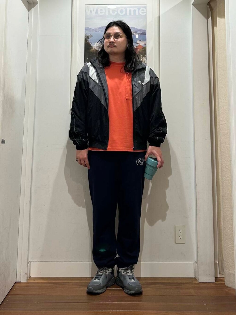 オレンジ系のTシャツ/カットソー、ブルー系のその他パンツ、ブラック系のナイロンジャケットを着用したメンズの夏コーディネートの1枚目の写真