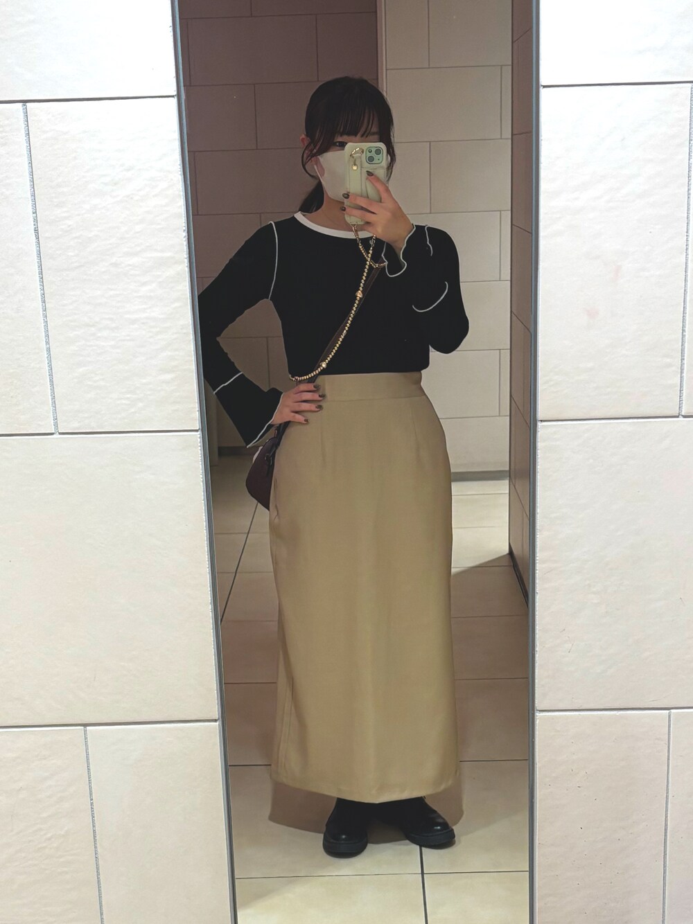 ベージュ系のスカート、ブラック系のTシャツ/カットソーを着用したレディースの秋コーディネートの1枚目の写真
