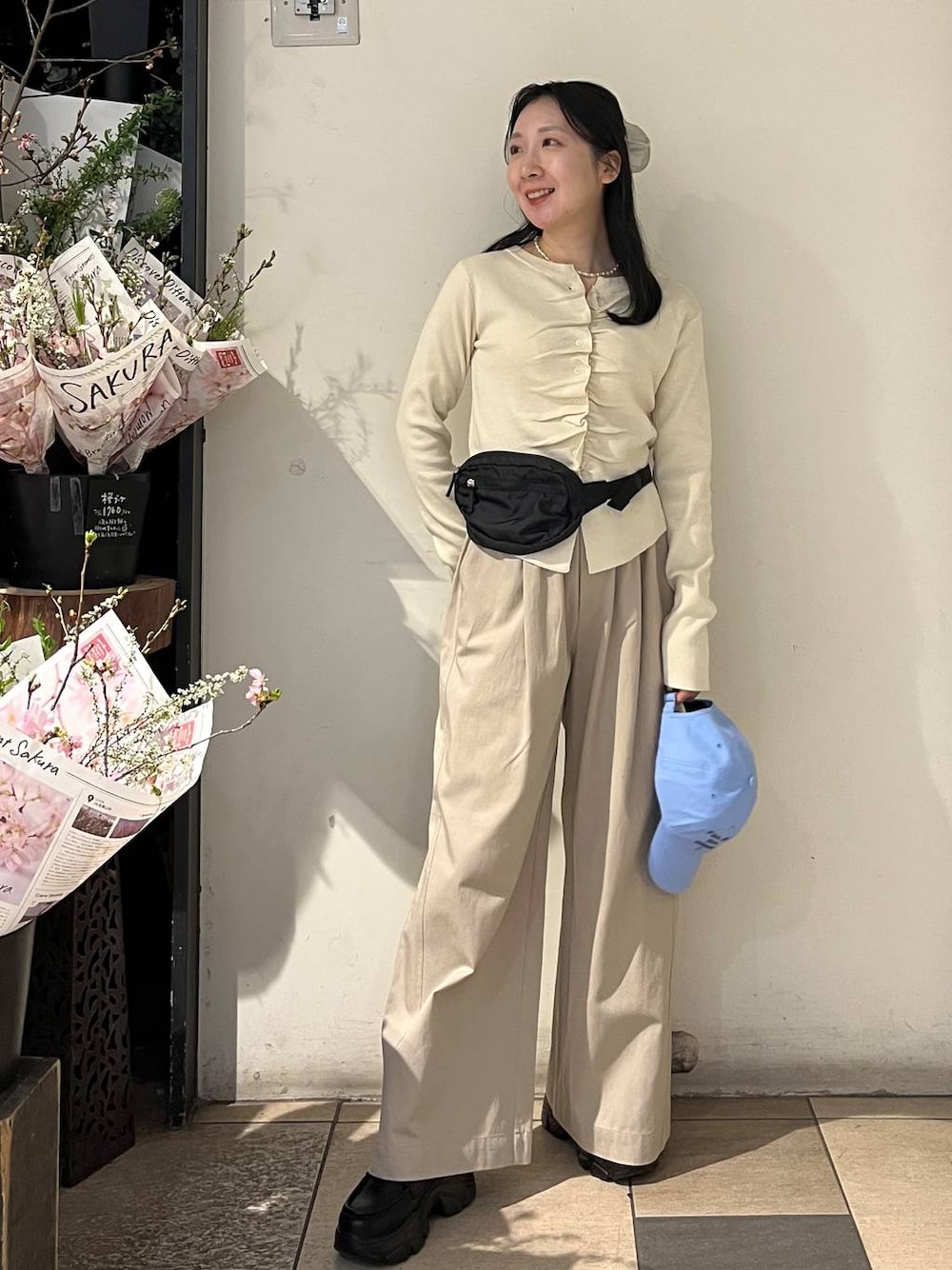 ベージュ系のデニムパンツ、ブラック系のローファー、ブラック系のボディバッグ/ウエストポーチを着用したレディースの春コーディネートの1枚目の写真