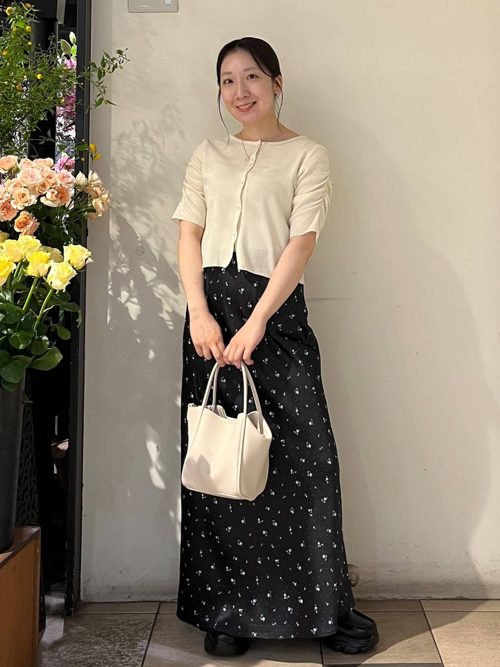 ブラック系のスカート、シルバー系のタンクトップ、ホワイト系のショルダーバッグを着用したレディースの春コーディネートの1枚目の写真