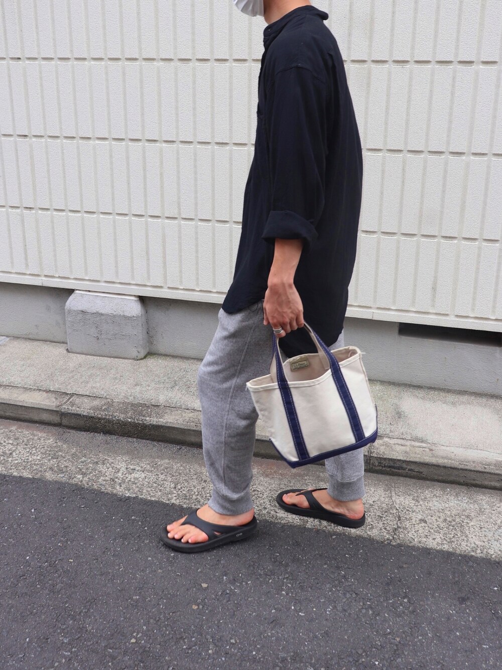 グレー系のスウェットパンツ、ブルー系のトートバッグ、ブラック系のサンダルを着用したメンズの夏コーディネートの1枚目の写真