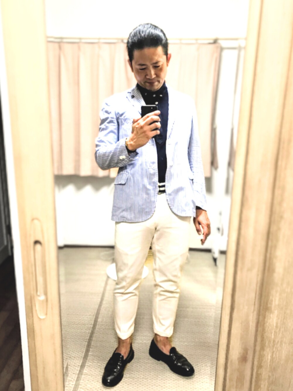 ブルー系のテーラードジャケット、ブルー系のポロシャツ、ホワイト系のチノパンツを着用したメンズの夏コーディネートの1枚目の写真