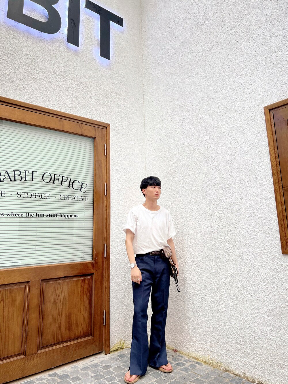 ホワイト系のTシャツ/カットソー、ブルー系のスラックス、ベージュ系のサンダルを着用したメンズの秋コーディネートの1枚目の写真