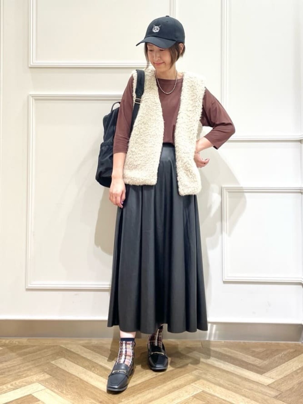 ベージュ系のベスト、ブラウン系のTシャツ/カットソー、ブラック系のスカートを着用したレディースの秋コーディネートの1枚目の写真
